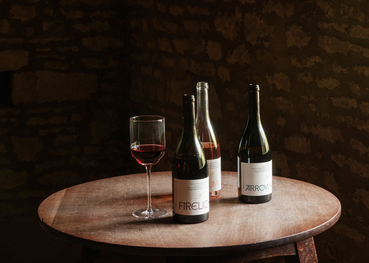 Knollbury Fort wine bottles and a glass on a wooden table with a dark background